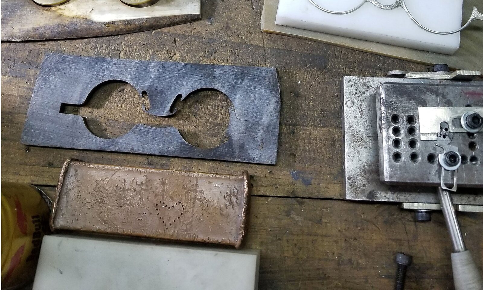 The Rigards atelier bench: horn blanks, a frame cut from horn, the steel template for a round frame, a copper sheet
